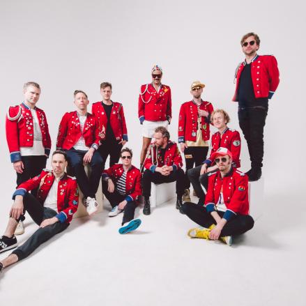 Band MEUTE bei einem Fotoshooting. Die Musiker tragen markante rote Jacken und stehen in dynamischer Pose zusammen. Foto: shotbywozniak.
